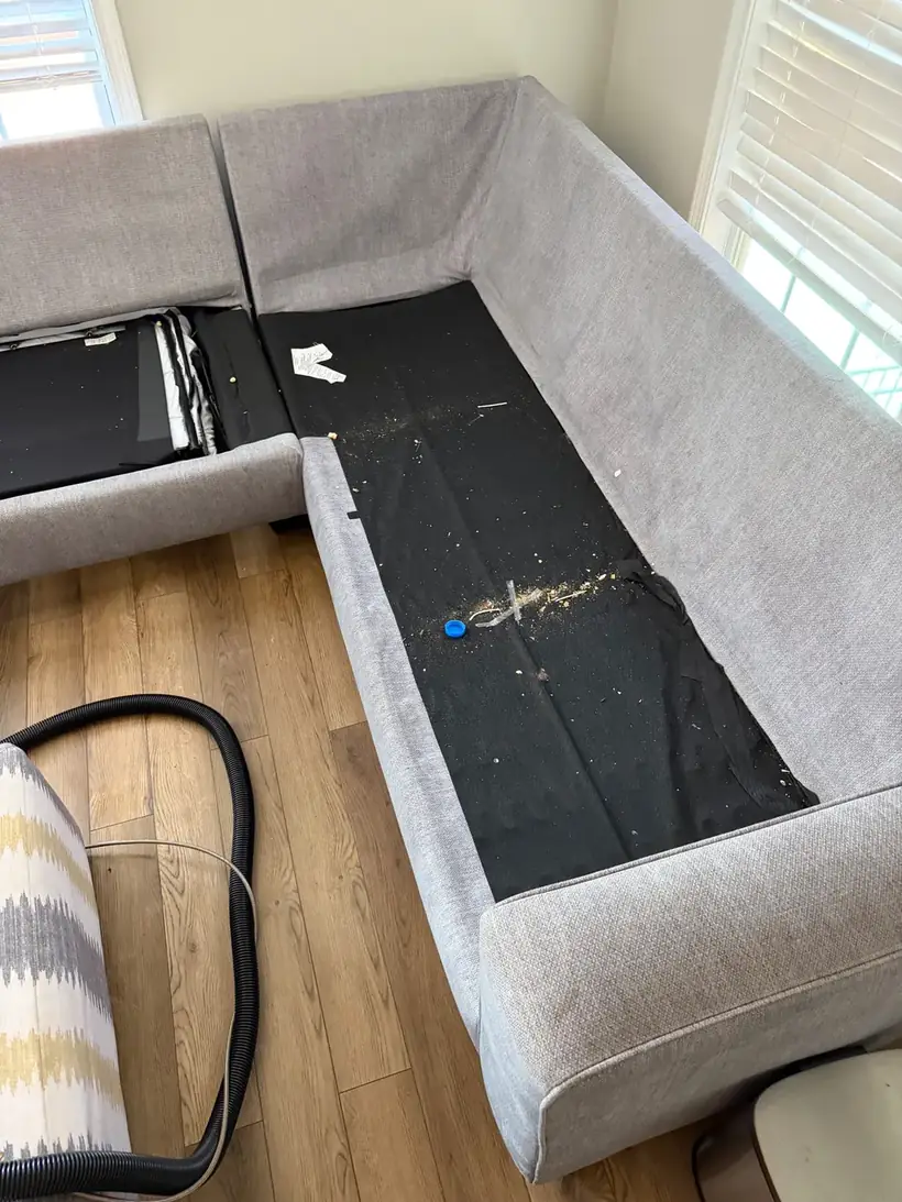 Crumbs and debris under the cushions of a sectional sofa before cleaning, Atlanta GA