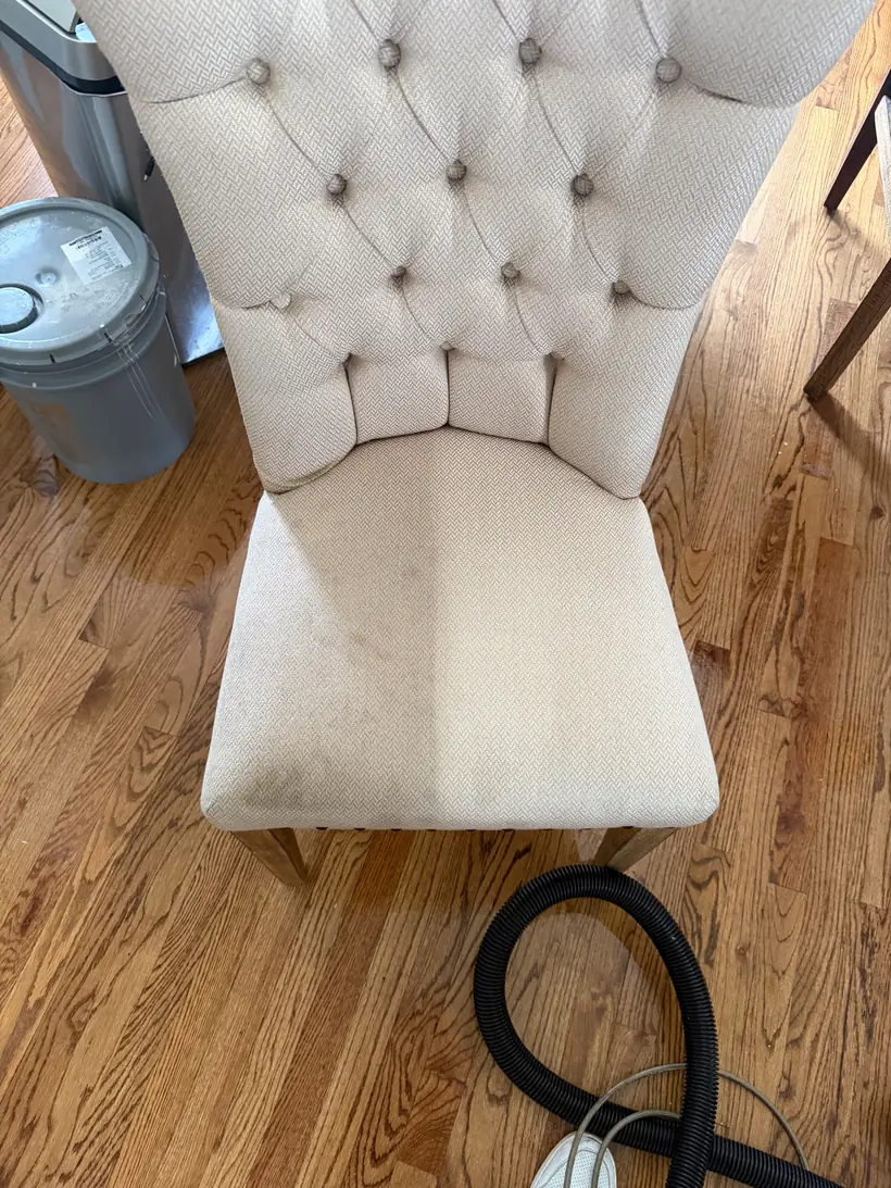 Cream button-tufted dining chair part-way through cleaning by Factory Fresh LLC in Atlanta GA